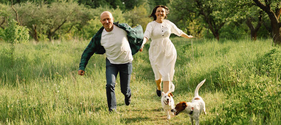 active older couple running with dogs