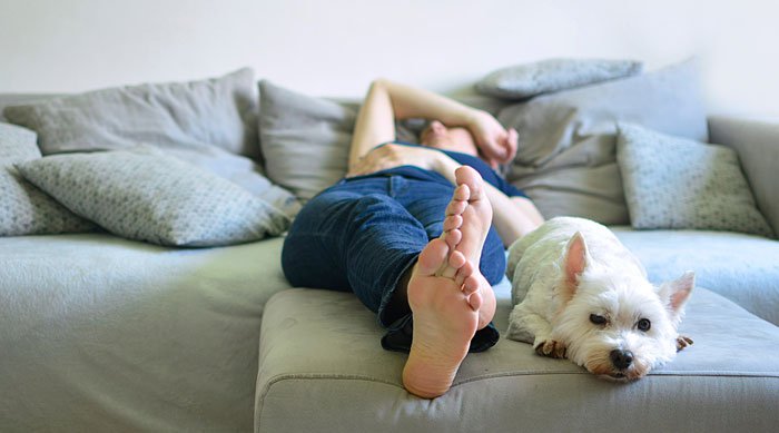 Woman lying on couch with Scottish Terrier