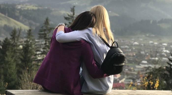 Friends hugging overlooking valley town