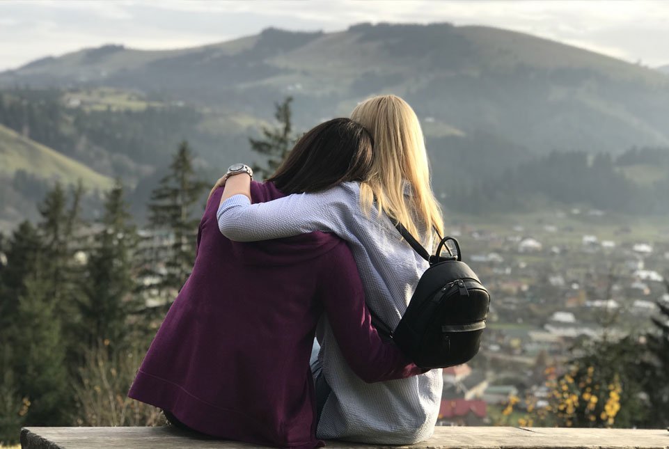 friends hug overlooking town and mountains